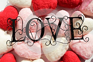 black wire LOVE word, with spread out red, pink white pillow hearts.