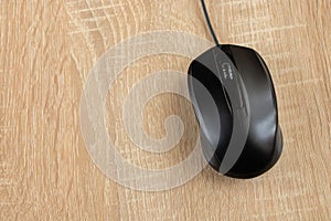 Black wired computer mouse on a wooden table