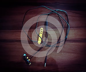 Black wired earphone in dark background. Earphones with a tangled wire.