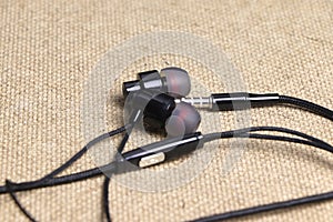 Black wired headphones for mobile phone on a wooden background