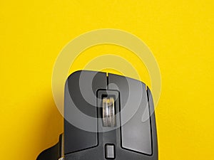 Black wireless computer mouse scroll wheel on yellow background