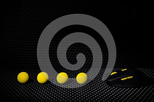 Black wireless computer mouse with yellow buttons on a background of black lattice