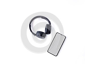 Black wireless headphone and mobile smartphone with a blank screen mockup lay on the surface of a white background