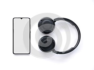 Black wireless headphone and mobile smartphone with a blank screen mockup lay on the surface of a white background