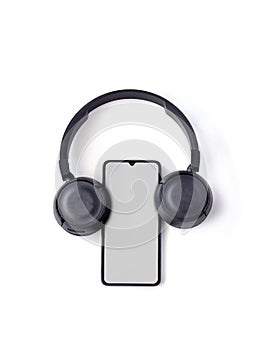 Black wireless headphone and mobile smartphone with a blank screen mockup lay on the surface of a white background