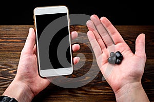 Black wireless headphones and mobile phone on dark wooden background