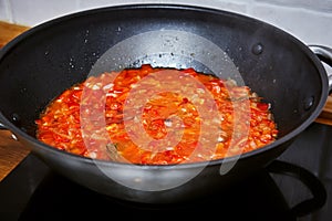 Black wok with vegetable sauce on the stove. Close-up