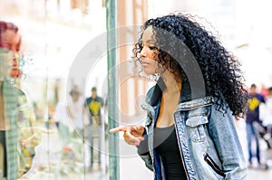 Black woman, afro hairstyle, looking at the shop window