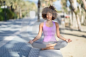 Black woman, afro hairstyle, in lotus asana with eyes closed in