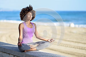 Black woman, afro hairstyle, in lotus pose with eyes closed in t photo