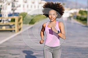 Black woman, afro hairstyle, running outdoors in urban road.