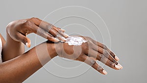 Black woman applying body lotion to her hands