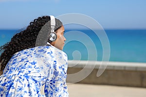 Black woman on the beach wearing headphone contemplating