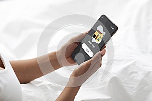 Black woman in bed login smart home system on cellphone