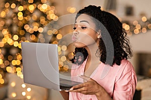 Black woman blowing kiss during virtual date on laptop