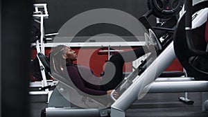 A black woman with braids sits down on a exercise equipment for legs and starts training