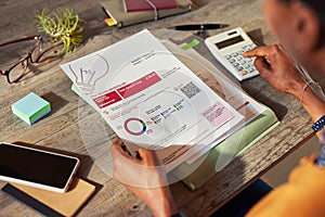 Black woman calculating bills at home on wooden table