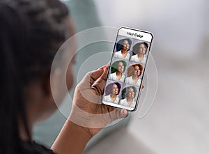 Black woman checking hair color simulation mobile application on smartphone