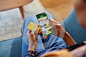 Black woman choosing a meal on food delivery app on smartphone at home