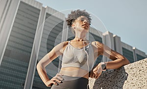 Black woman, city fitness and music earphones for sports motivation, exercise and workout in urban town from below