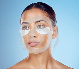 Black woman with collagen eyes mask isolated on blue background for skincare, beauty and facial cosmetics. Young model