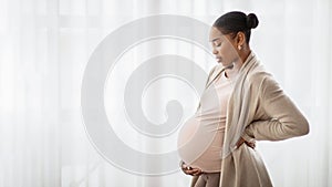 Black woman in comfortable homewear standing next to window