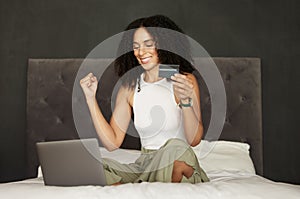 Black woman, credit card and laptop on bed for ecommerce, celebration and discount on internet. Woman, online shopping