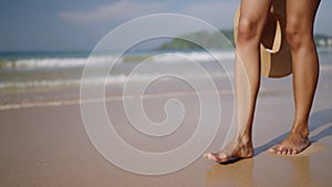 Black woman feet walking on sandy ocean beach at exotic island along sea water waves. Dark skin female legs go by surf