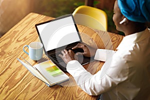 Black woman freelancer typing on laptop with blank screen, mockup