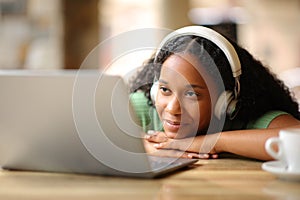 Black woman with headphone watching media content on laptop