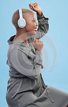Black woman, headphones and dancing in studio profile, happy and listening by blue background. African dancer girl