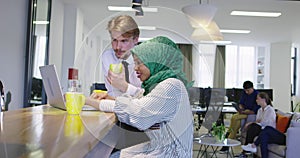 Black woman with hijab meeting business man in casual startup office, man eating apple on meeting