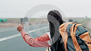 Black woman, hike and thumbs up on highway for road trip journey or adventure, tour with hitchhiking to see countryside