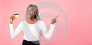 Black woman holding credit card and pointing at free space