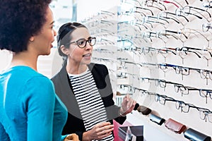 Black woman inspecting glasses in optician shelf