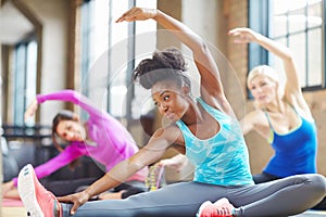 Black woman, instructor and yoga class at gym, stretch and yogi trainer for exercise on mat. Female person, floor and
