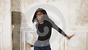 Black woman in jeans and pullover dances in high heels