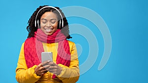 Black Woman Listening Music On Phone Standing Over Blue Background