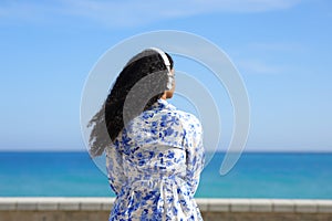 Black woman listening to music contemplating ocean