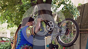 Black woman maintaining bicycle pedal