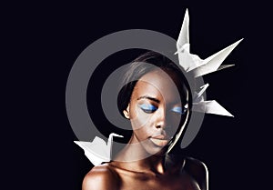 Black woman, makeup and fine art with beauty, dove or origami birds on a dark studio background. Closeup or face of