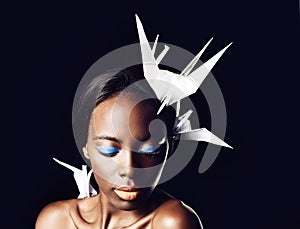 Black woman, makeup and fine art with cosmetics, origami birds or dove on a dark studio background. Closeup or face of