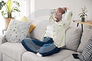 Black woman, meditation and listening to podcast to relax with headphones in home, living room or peace on sofa. Music