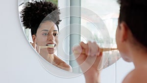 Black woman, mirror and brushing teeth for clean, health and hygiene in morning while home. Woman, start and cleaning