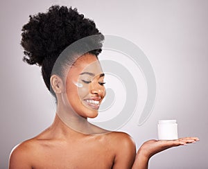 Black woman, moisturizer cream and smile for skincare beauty or cosmetics against a gray studio background. Happy