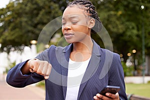 Black woman, phone and time management for business schedule while outdoor with a watch at a park waiting for a meeting