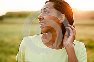 Black woman with pigtails smiling and looking aside outdoors