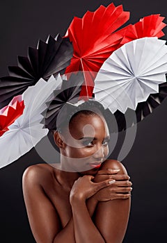 Black woman, portrait and smile with origami fans in studio isolated on a dark background. Face, makeup cosmetics and