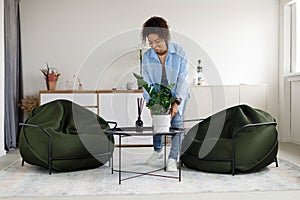 Black woman putting vase with plant on table