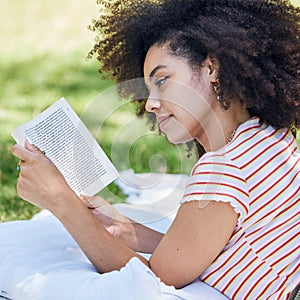 Black woman reading book, relax in park and picnic blanket with novel in nature. Education, learning and female student